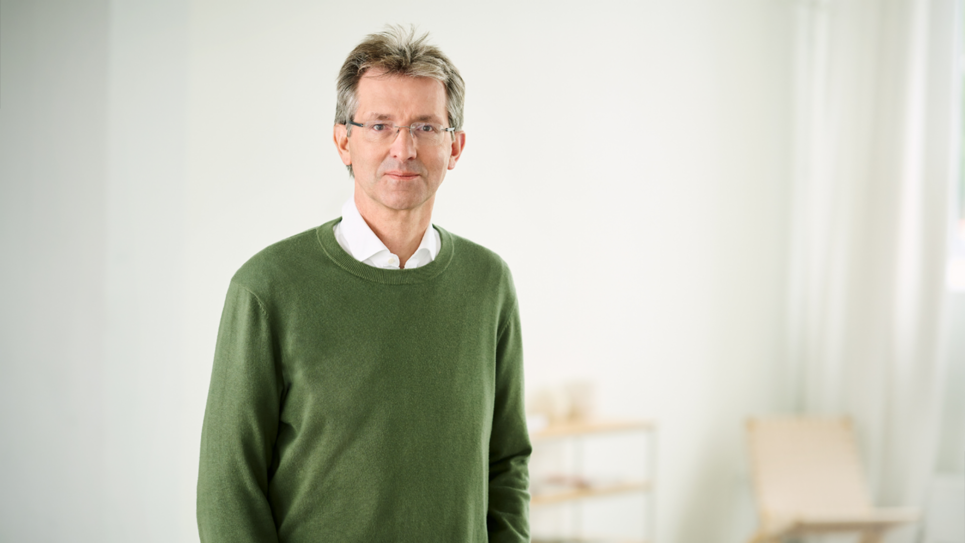 Justus Heking-Feltman, finansijski direktor, stoji u osvetljenoj prostoriji u tamnozelenom džemperu i beloj košulji.