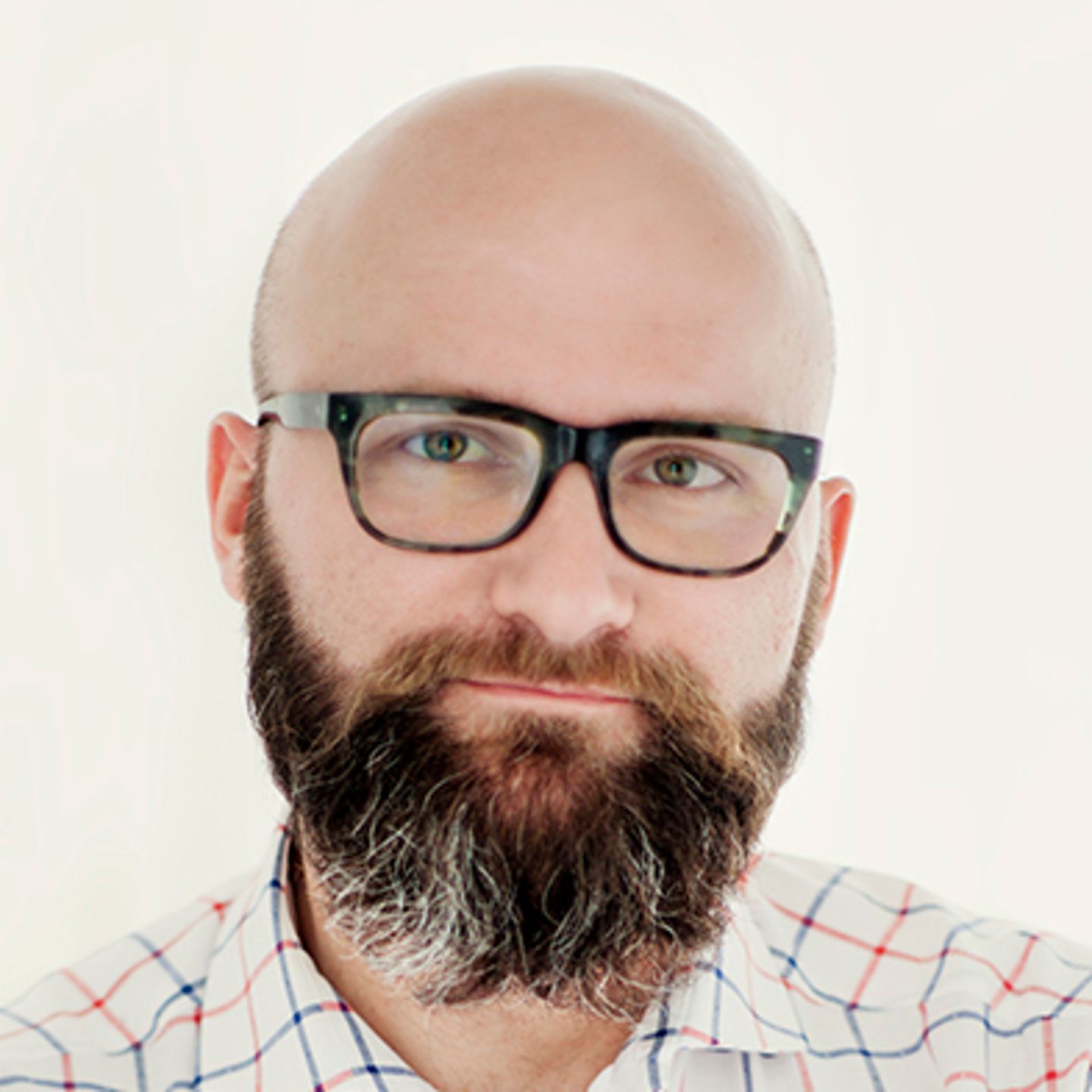 Dr. hab. Tomasz Piekot, u kariranoj košulji, oslonjen je na zid sa prekrštenim rukama.