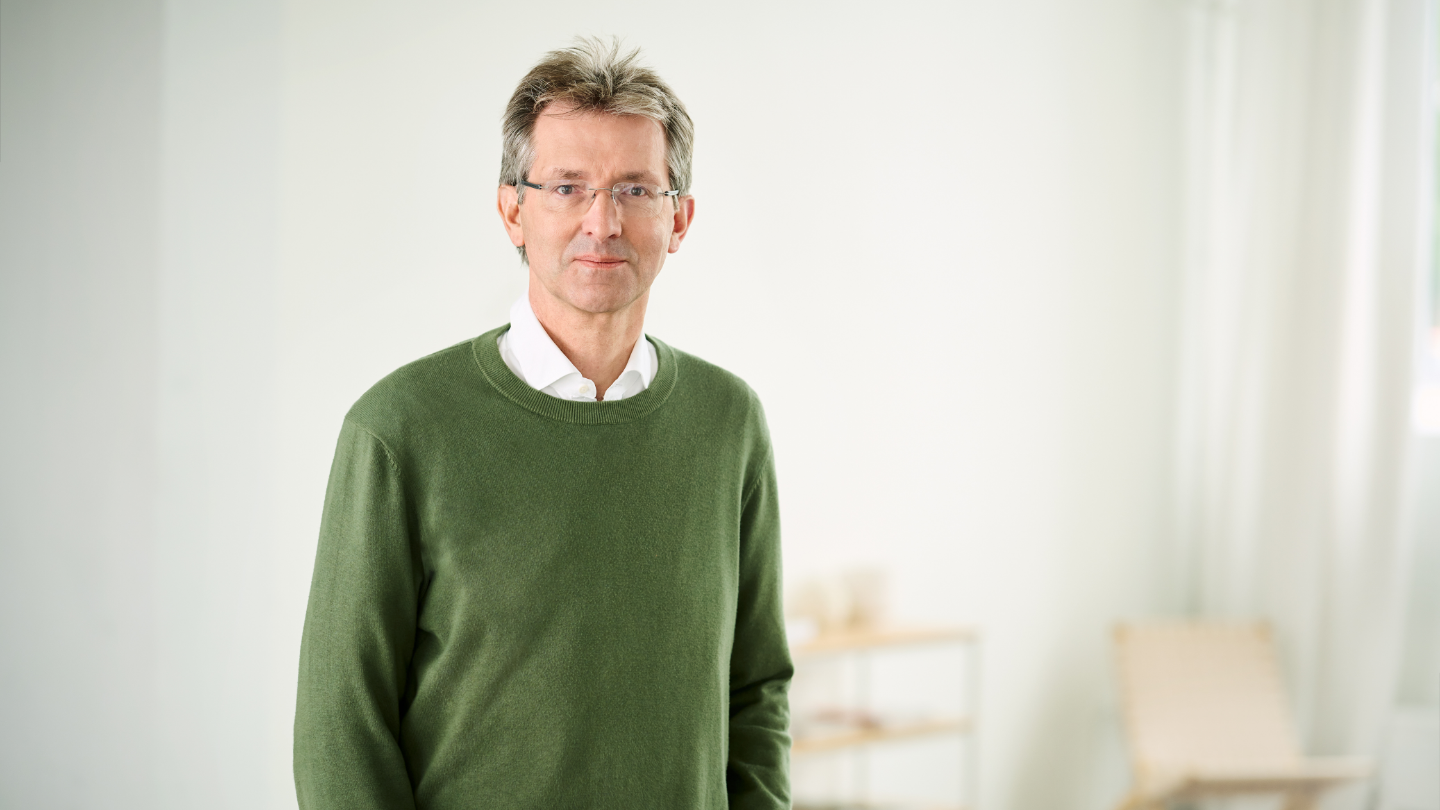 Justus Heking-Feltman, finansijski direktor, stoji u osvetljenoj prostoriji u tamnozelenom džemperu i beloj košulji.