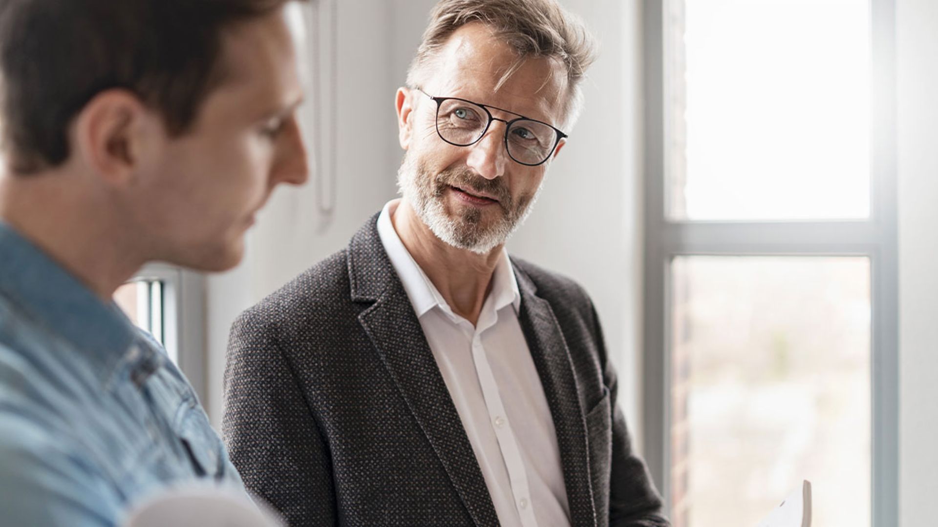 Dva muškarca u kancelariji razgovaraju o rezultatima studije EOS Grupe „Evropske platne prakse 2025“ o digitalizaciji u upravljanju potraživanjima.