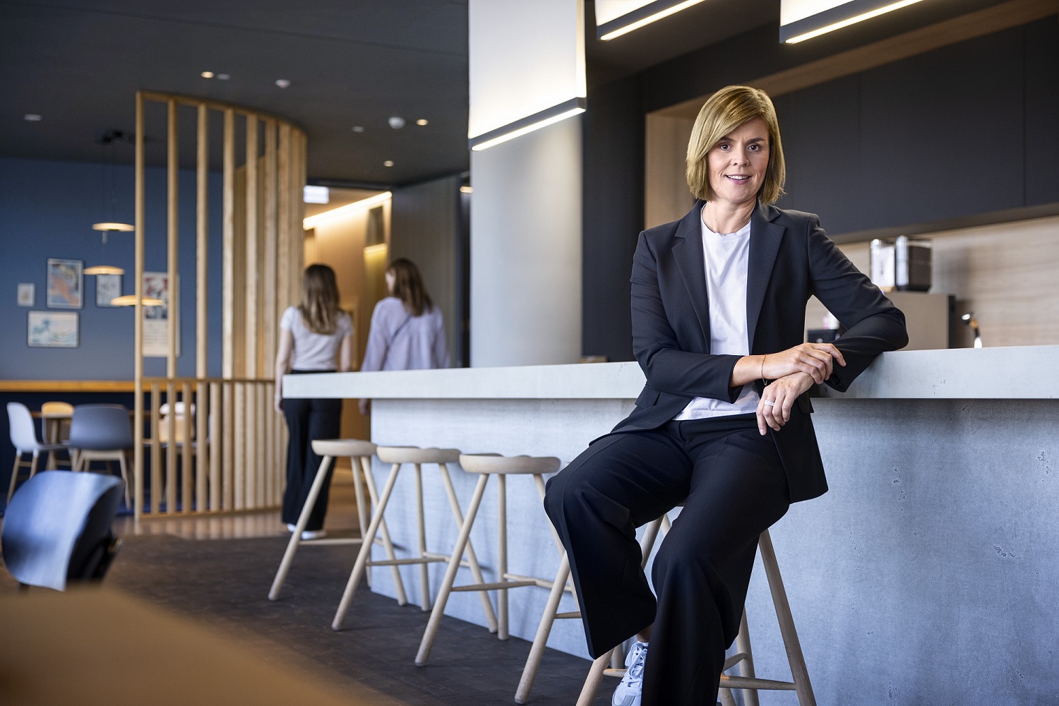 Dr. Eva Griewel, finansijska direktorka (CFO) grupe EOS, sedi u društvenom prostoru na visokom stolu, obučena u crni bleyzer.