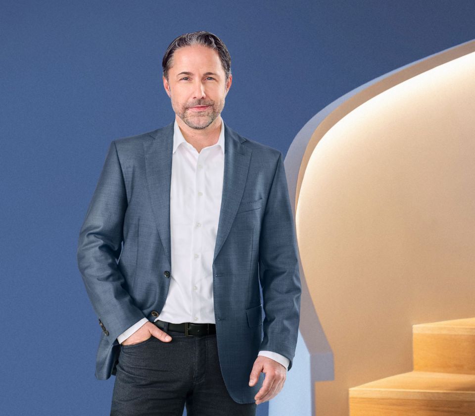 Marwin Ramcke, CEO EOS Grupe, stoji ispred plave pozadine, obučen u tamno odelo. Njegov pogled je usmeren direktno ka kameru.