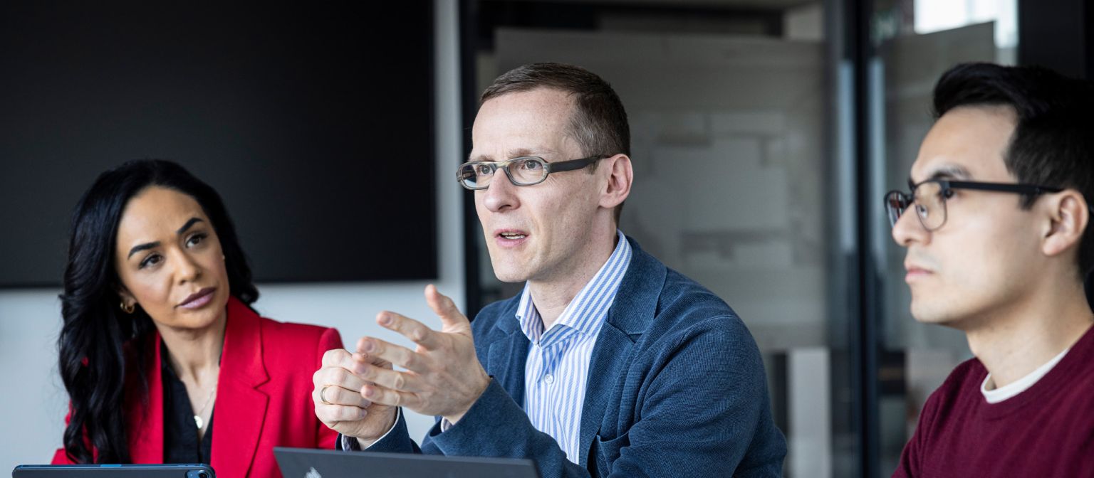 Three people are having a conversation in an office.