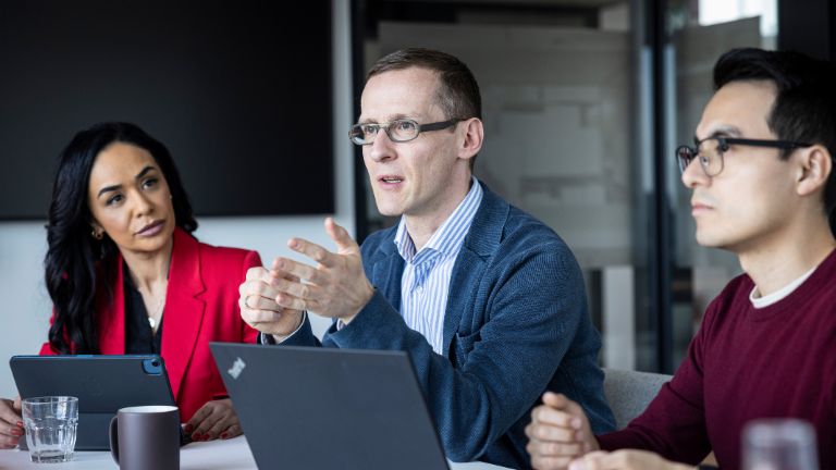 Three people are having a conversation in an office.